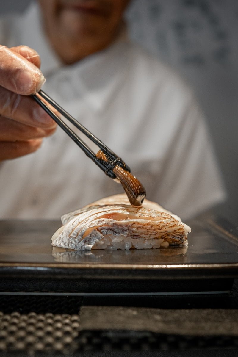 nigiri - a person holding chopsticks over a piece of food